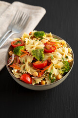 Yummy Homemade Vegan Pasta Salad with Tomato, Onion, Carrot, Broccoli, Chickpeas and Parsley in a Bowl, side view.