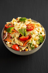 Yummy Homemade Vegan Pasta Salad with Tomato, Onion, Carrot, Broccoli, Chickpeas and Parsley in a Bowl, side view.