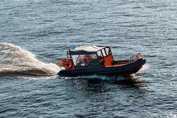 Fototapeta premium The rescue boat floats at speed through the water. Rigid inflatable boat with lifeguards on duty in coastal waters.