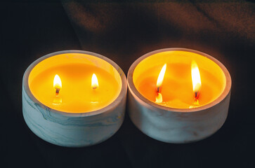 Fototapeta na wymiar Decorative candles burn in the apartment on black background