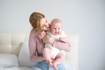 young mother holds her smiling baby in her arms at home 