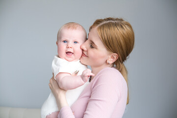 young mother holds her smiling baby in her arms at home 