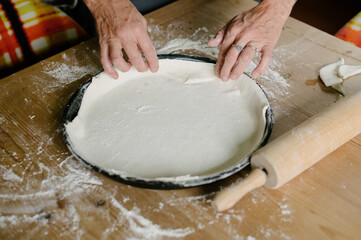 Unrecognizable woman standing at table and folding extra dough on baking pan