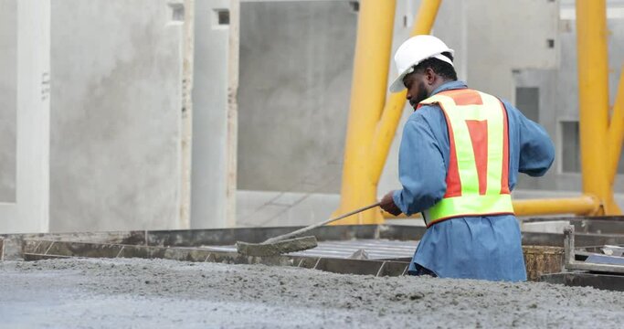 African american mason worker pouring the ready-mixed concrete at Heavy Industry Manufacturing Prefabricated concrete walls factory