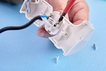 Assembly of folding electrical plug for an electrical cord, an electrician assembles plastic electric connector of European standard type f. - obrazy, fototapety, plakaty