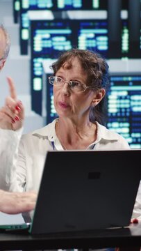 Vertical video Aged coworkers looking around modern server farm, preparing to start comission on malfunctioning high tech workspace hardware clusters in order to ensure proper operations