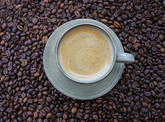 Cup with coffe on the roasted coffe beans.