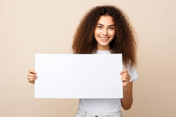 Fototapeta premium Happy young woman holding blank white banner sign, isolated studio portrait .
