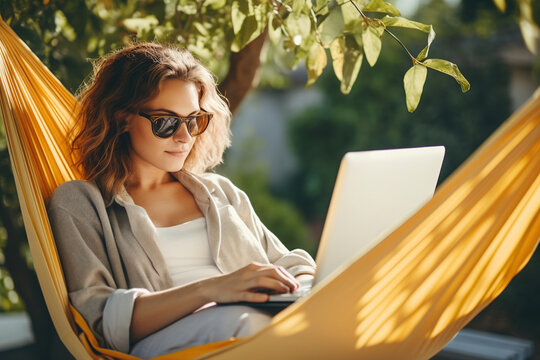 Woman using laptop outdoor. Young beautiful girl in a hammock and working on computer. Freelance, summer, enjoy life, student lifestyle, distance studying, travel vacations.