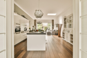 a kitchen and dining area in a modern home with wood flooring, white cabinets and an open door leading to the living room