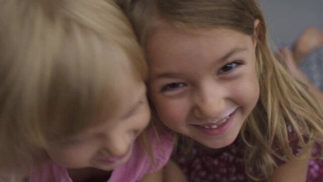 Close-up of two happy child girls after drinking milk smiling looking at camera 4K