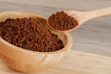 Wooden Bowl with fresh ground Roasted Coffee Grounds wooden background