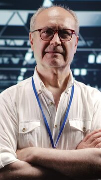 Vertical video Portrait of senior technician looking around modern server hub in data center, preparing to start comission on malfunctioning high tech workplace hardware racks in order to ensure