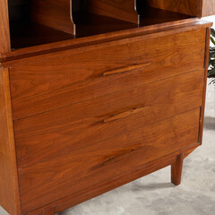Wooden set of drawers. Mid-Century Modern hutch cabinet with tapered pulls. Close-up product photograph.