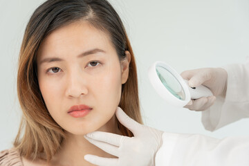 skin problem and beauty of asian girl. Dermatologist use magnifying glass look itchy skin from skin allergic, steroid allergy, sensitive skin, chemical allergy, rash, insect bites, Dermatitis.