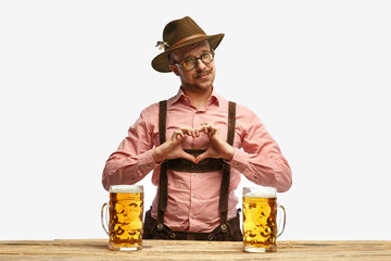 Man with mustaches wearing traditional german outfit showing heart symbol shape feelings on holiday...