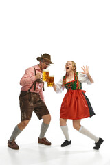 Two celebrating friends. Shouting man and woman wearing traditional German outfits, having clinking glasses with Bavarian beer.
