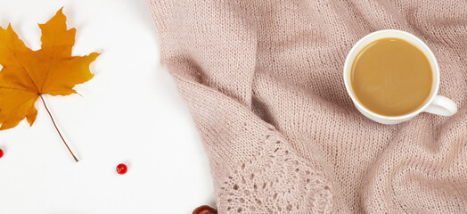 Hello autumn flat background. Top view of a sweater, a cup of coffee,yellow leaves and a white background