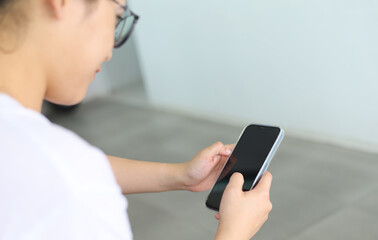 A woman sitting in a restaurant looks at the screen of her cell phone and reads a message. Woman hands with smartphone for online shopping and payment. Shopping service on online web. Spending money.