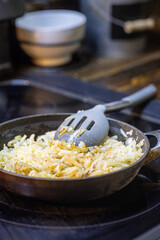 Shredded hash browns cooking in cast iron skillet