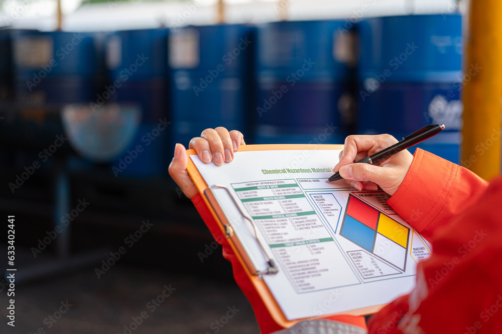 Wall mural a safety officer is checking on the hazardous material checklist form with chemical storage area at 