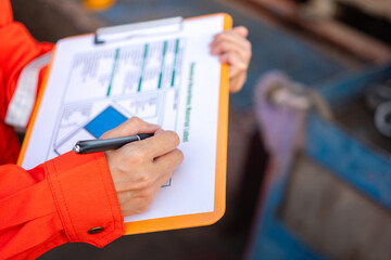 Action of a supervisor is using a pen to writing on chemical hazardous material paper form to...