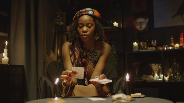 African American tarot specialist doing layout on camera sitting in studio with burning candles