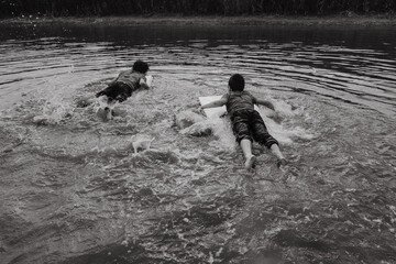 Happy boys swimming with board over water