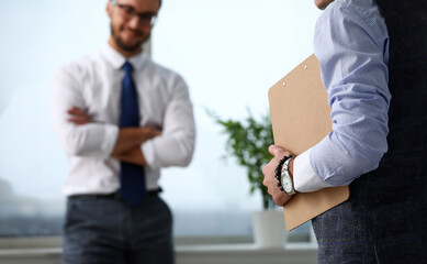 Male clerk arm in suit and tie with paper clipped to pad at office workplace closeup. Strike...