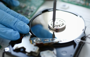 Male repairman wearing blue gloves dismantles specialized professional screwdriver hard drive....