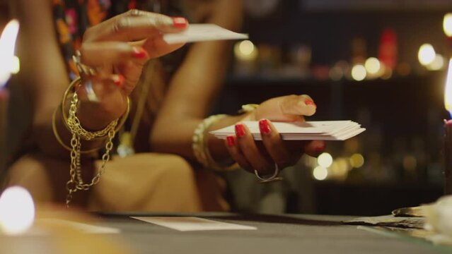 Cropped shot of seer looking at tarot cards when doing layout in studio with burning candles