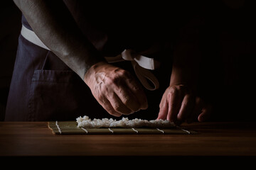 Male shushi man hands preparing different pieces of makis