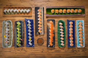 Set of sushi rolls on plates on wooden table in restaurant