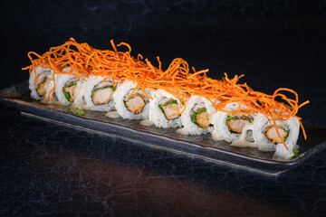 Tasty sushi rolls with shredded carrot on marble tray