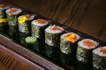 Appetizing sushi rolls with salmon and pepper on tray