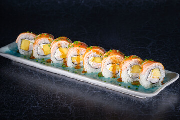 Delicious sushi rolls on marble plate in dark studio