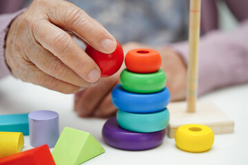 Fototapeta premium Asian elderly woman playing puzzles game to practice brain training for dementia prevention, Alzheimer disease.