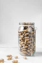 shelled groundnut in a glass jar, peanuts in shell in a transparent jar on a marble countertop, nigerian roasted groundnut in a glass container