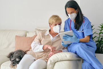Obraz premium Doctor sharing tablet with elderly patient during examination in