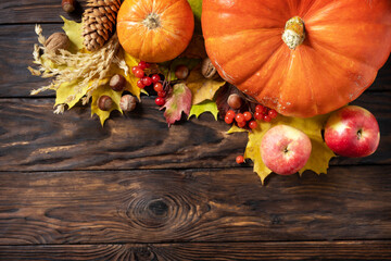 Autumn Day Thanksgiving or Halloween background. Festive autumn decor from ripe pumpkins, berries and leaves on a wooden background. View from above. Copy space.