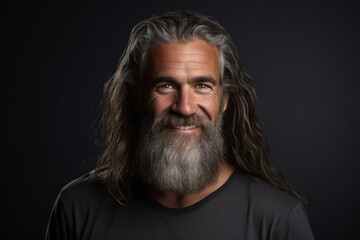 Fototapeta premium A smiling middle-aged European man with a long beard against a gray studio background.