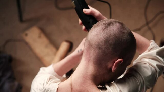 A woman shaves off her hair. Back view.