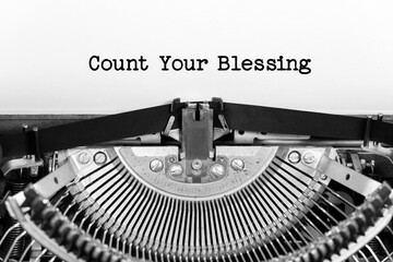 Count Your Blessing phrase closeup being typing and centered on a sheet of paper on old vintage typewriter mechanical