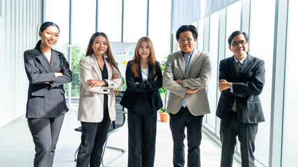 Asian male and female work team in suits standing with arms crossed arms crossed ready to serve and proud of work success business professional standing in company conference room