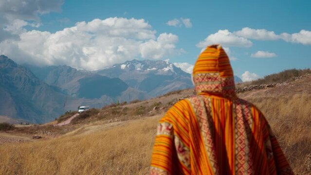 Persona caminando con traje tipico per&uacute;ano en cultivo de trigo con monta&ntilde;as cubiertas de nieve de fondo (Per&uacute;)