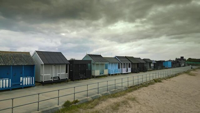 Aerial drone captures brightly coloured beach huts on Lincolnshire coast promenade.