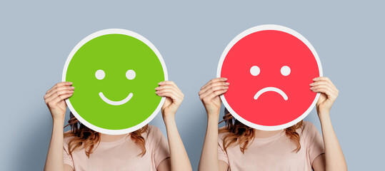 happy unhappy concept. two girls holding posters with happy and sad emotion - obrazy, fototapety, plakaty