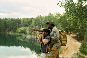 Little boy watching through the binoculars while travelling together with his dad