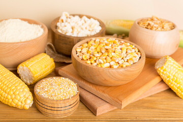 Maize products with fresh corn cobs on wooden table