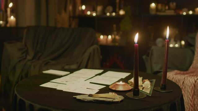 Fortune tellers studio with tarot layout and burning candles on table, mysterious atmosphere
